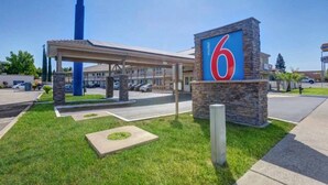 Ein Motel mit einem gut sichtbaren Schild mit der Zahl 6, einem überdachten Parkplatz und einem gepflegten Rasen.