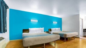 Ein Hotelzimmer mit zwei Betten, einer blauen Akzentwand und einem Holzboden.