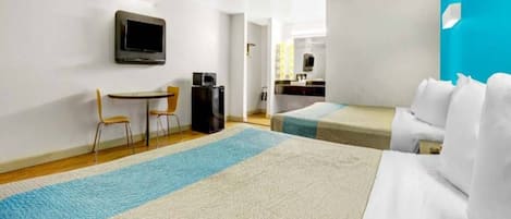 Ein Hotelzimmer mit Bett, Schreibtisch, Stuhl, Fernseher und einer Küchenzeile.
