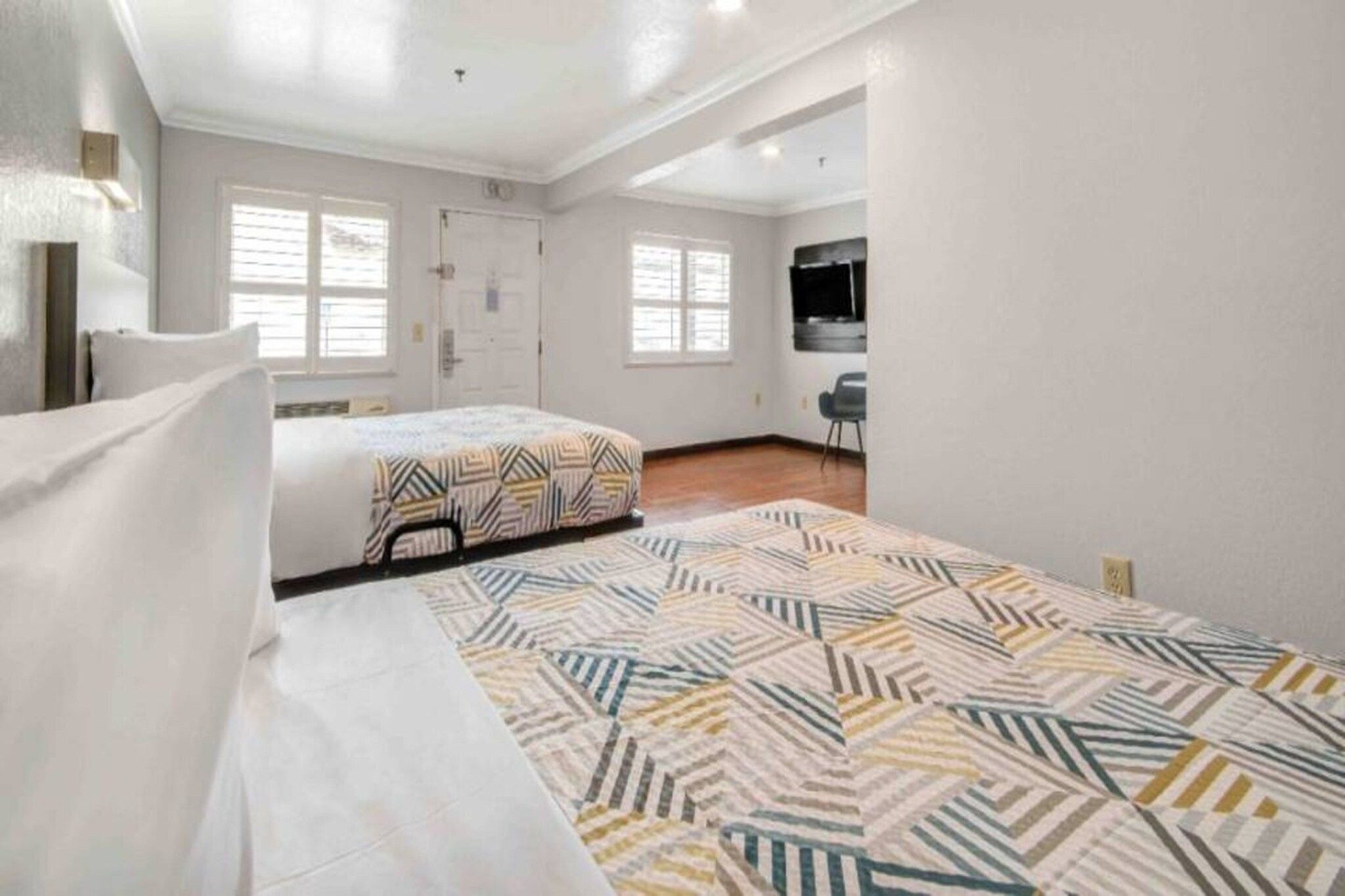 Quarto com duas camas, televisão e porta para um banheiro.