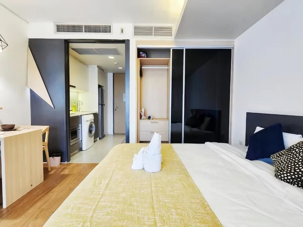 Quarto de hotel com cama, escrivaninha, máquina de lavar e armário.