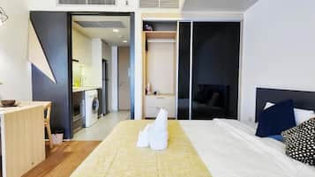 Quarto de hotel com cama, escrivaninha, máquina de lavar e armário.