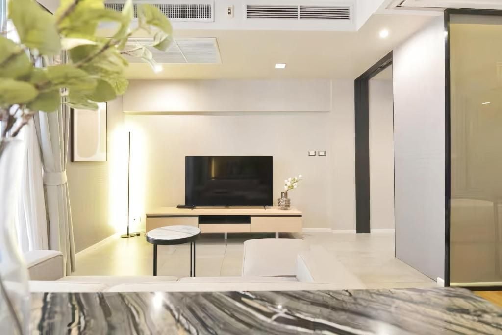 Een moderne woonkamer met een flatscreen televisie, een ronde salontafel en een bank.