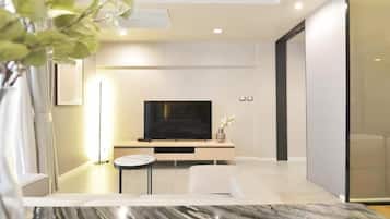 Een moderne woonkamer met een flatscreen televisie, een ronde salontafel en een bank.