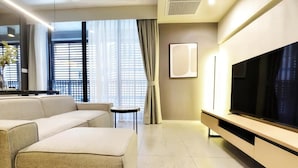 Una sala moderna con un sofá, un televisor y una mesita.