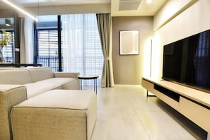 A modern living room with a sofa, a TV, and a small table. - Circle S Sukhumvit 12 Bangkok (Krung Thep Maha Nakhon)