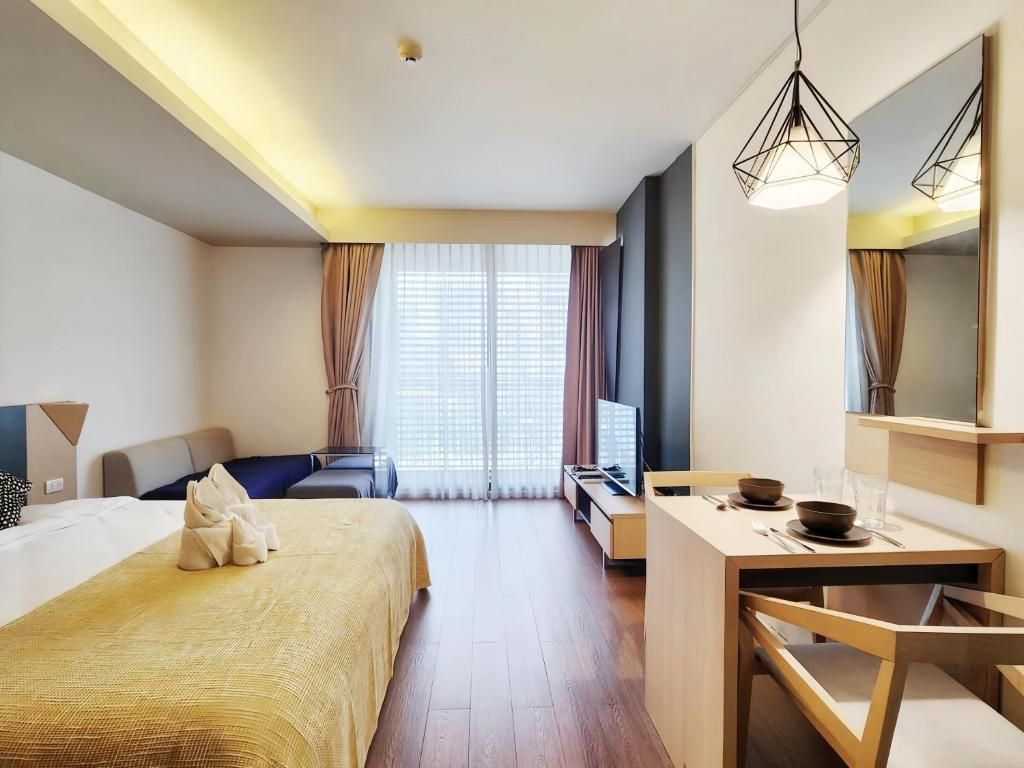 A hotel room with a bed, a desk, a chair, a television, and a large window with curtains.