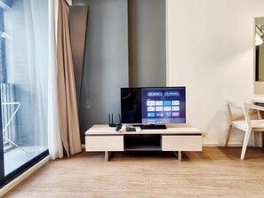 A modern living room with a flat-screen TV, a white entertainment unit, and a wooden floor.