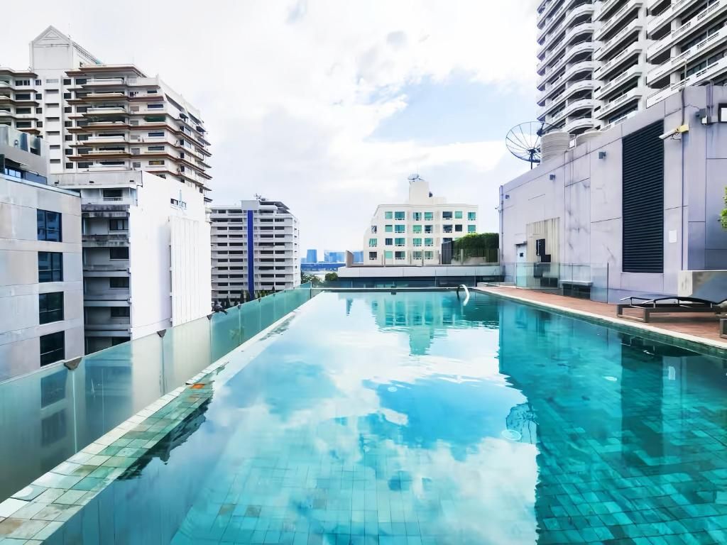 Piscina com borda de vidro, cercada por edifícios altos.