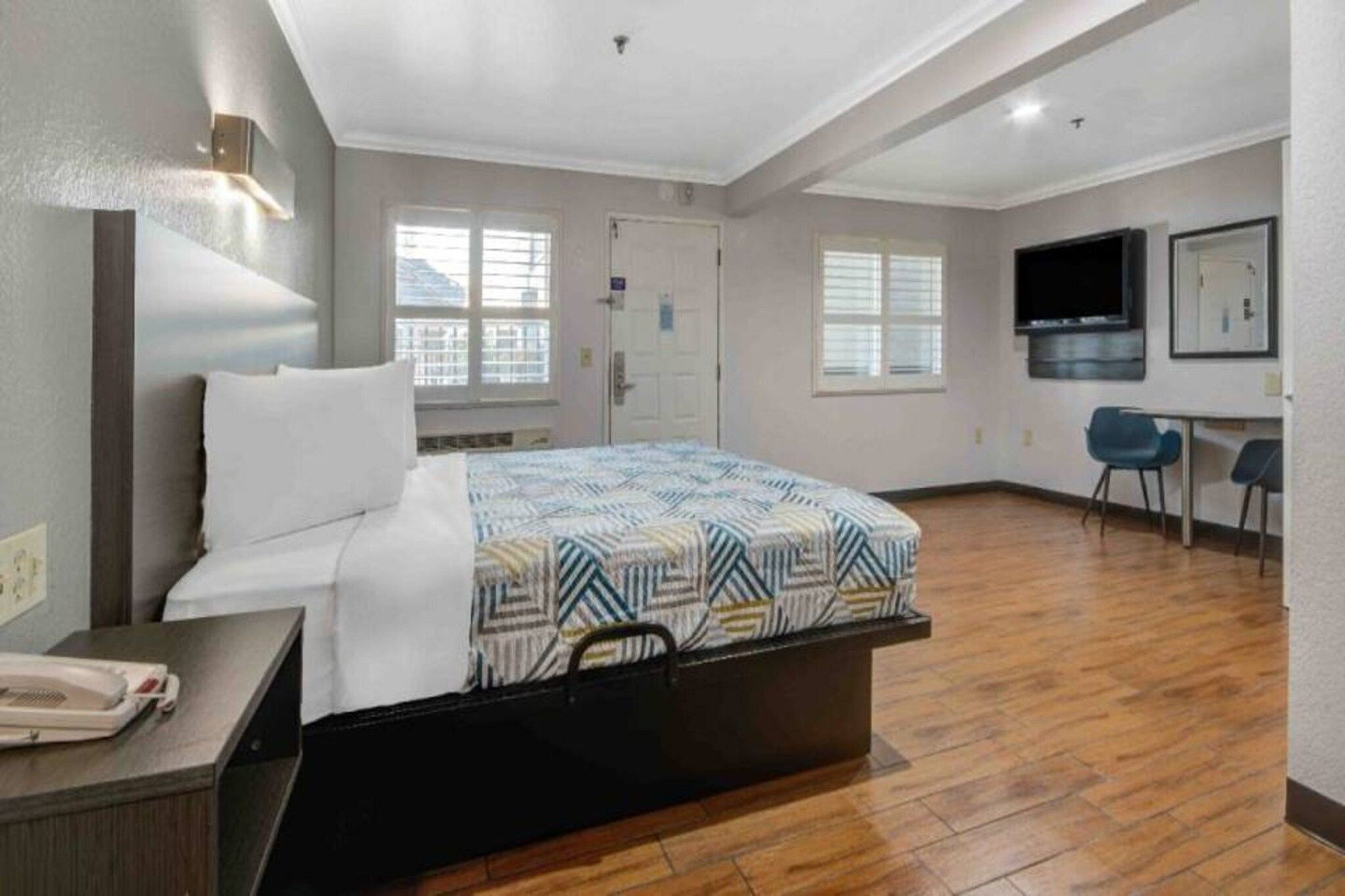 Una habitación de hotel con una cama, un escritorio con teléfono, un televisor y una ventana.