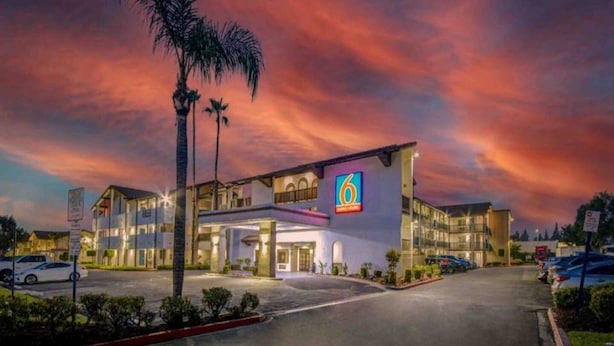 Un hotel con un llamativo letrero con el número '6', varios espacios de estacionamiento y una entrada bien iluminada.