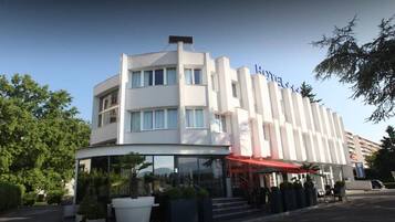 A hotel with a modern design, featuring a curved glass entrance and a red awning.