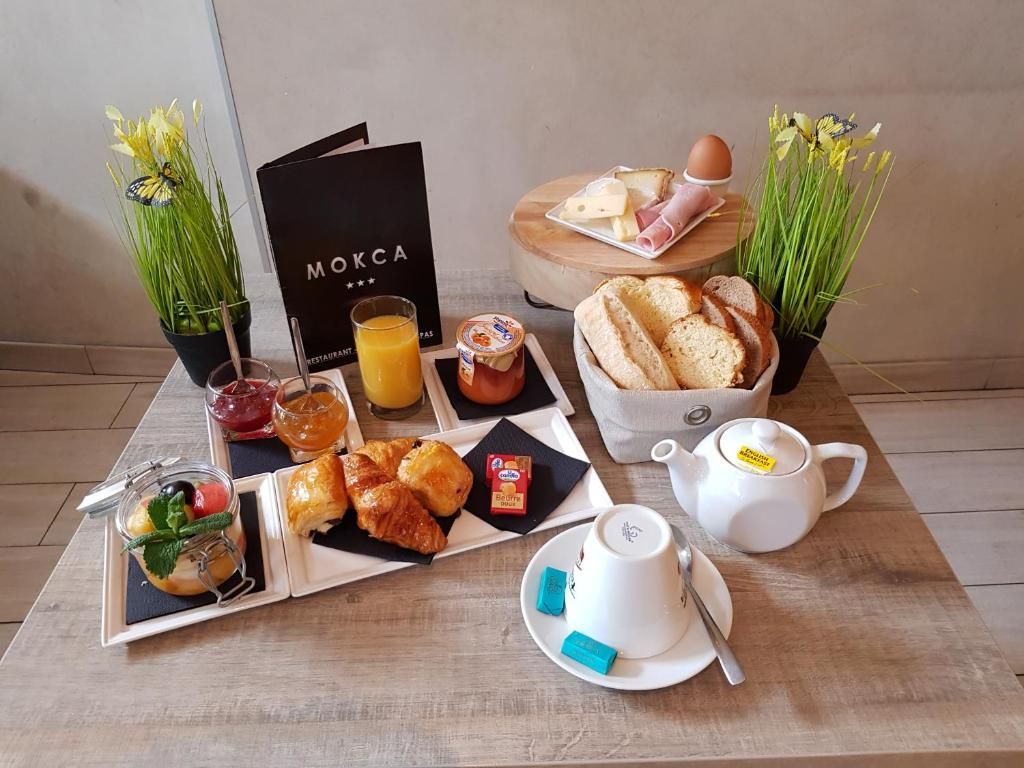 Desayuno con pan, bollería, un hervidor de té y un menú.