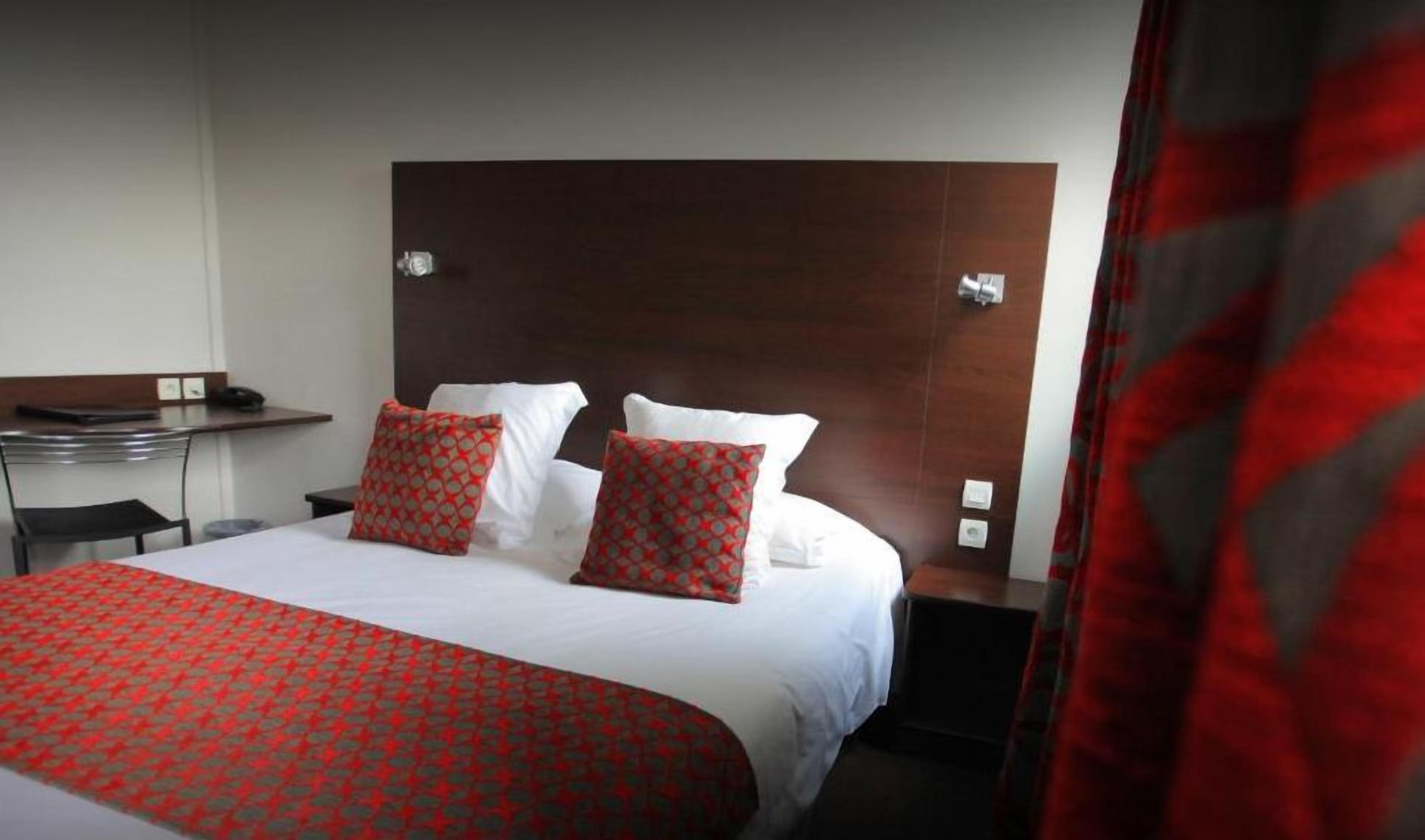 A hotel room with a large bed, a desk, and a chair.