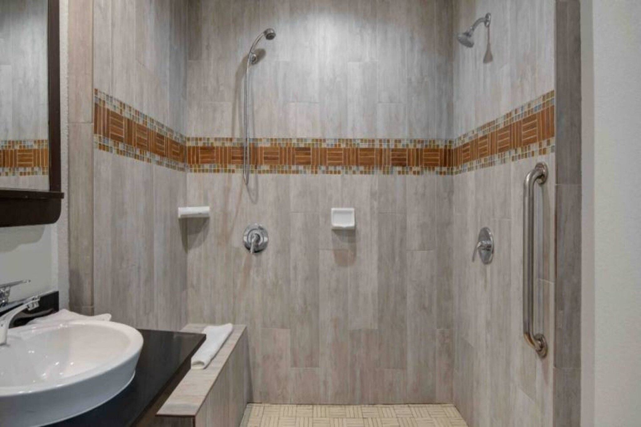 Ducha con pasamanos, lavabo y barra para toallas.