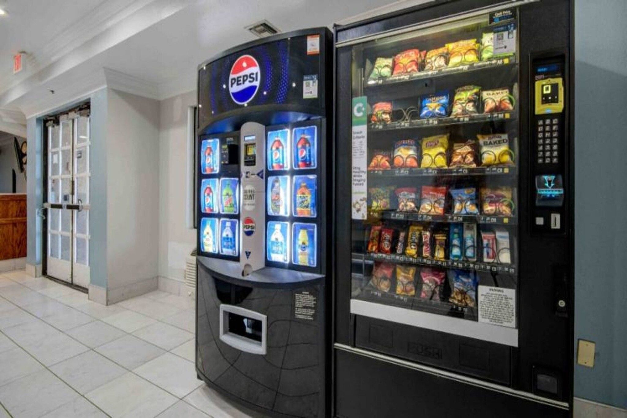 A vending machine with a Pepsi logo and a snack vending machine with various snacks.