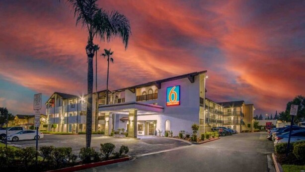 Un hotel con un llamativo letrero con el número '6', varios espacios de estacionamiento y una entrada bien iluminada.