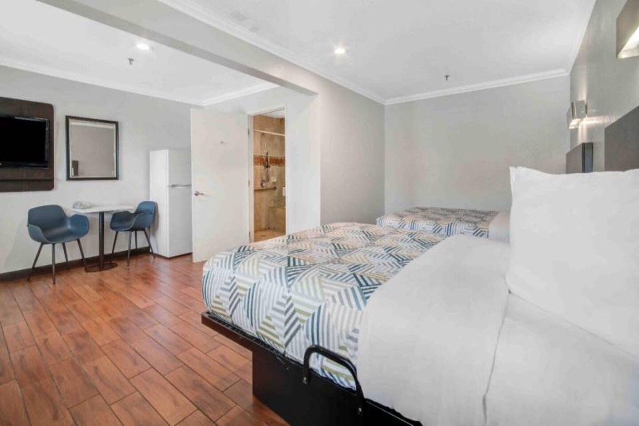 Quarto moderno com cama, escrivaninha, duas cadeiras e um closet espaçoso.