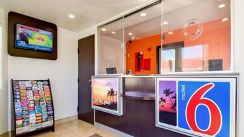 A hotel reception area with a digital screen, a magazine rack, and a sign for a motel.