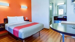 Ett hotellrum med en säng, ett runt bord och ett badrum som syns genom en öppen dörr.