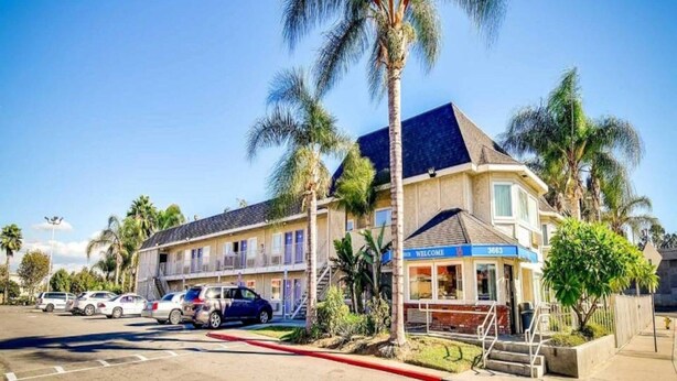 A motel with a two-story structure, a 'Welcome' sign, and a parking lot with several cars. - 2 Full Beds | Newly Redesigned, Nsmk, View (Riverside)