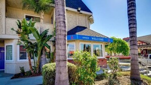 A hotel with a 'Welcome' sign, palm trees, and a clear blue sky. - 2 Full Beds | Non-Smoking (Riverside)