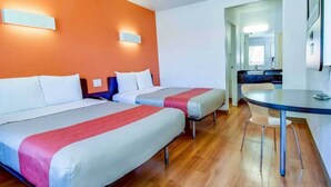 A hotel room with two beds, a small table, and a bathroom visible through an open door. - 2 Full Beds | Non-Smoking (Riverside)