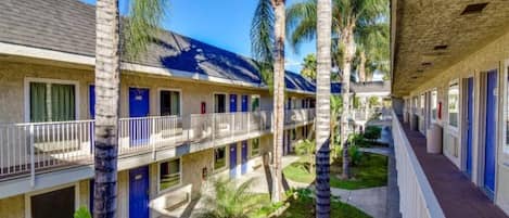 A motel with multiple rooms, a covered outdoor area, and palm trees.