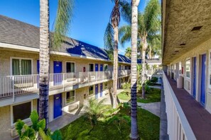 A motel with multiple rooms, a covered outdoor area, and palm trees.