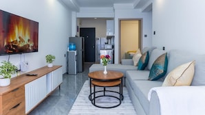 A modern living room with a sofa, a coffee table, a TV, and a kitchen area in the background. - JKIA Terminal Luxore  (Syokimau)