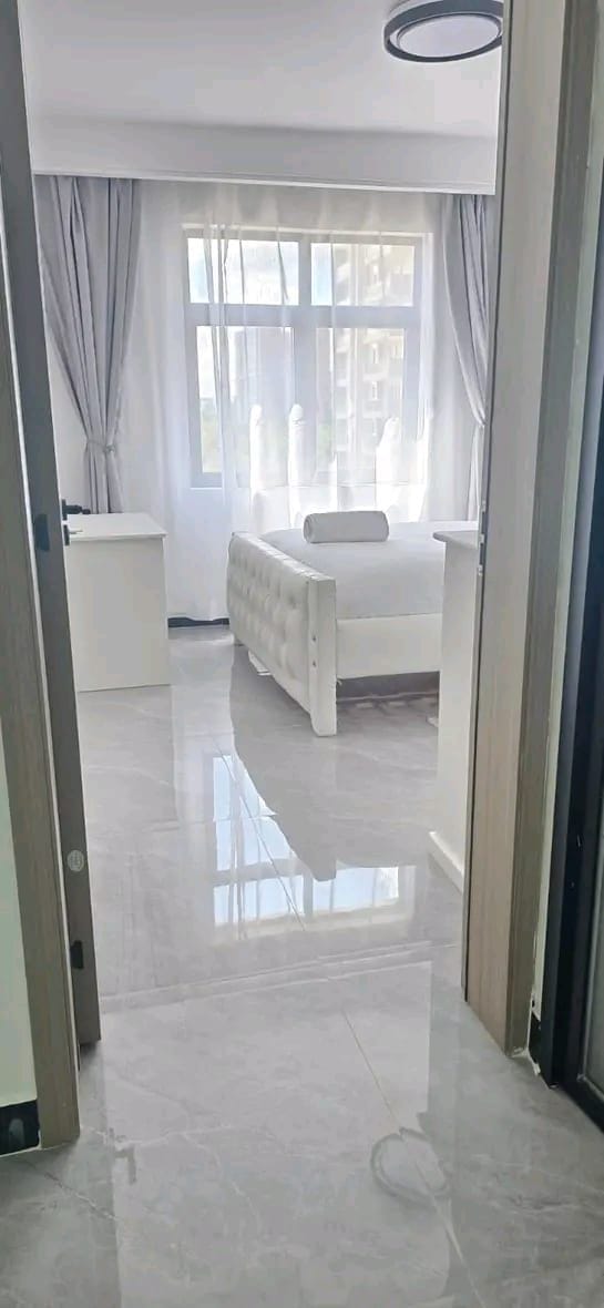 Una habitación de hotel con una cama, una mesita de noche y un ventanal con cortinas.