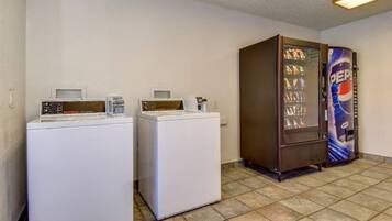 A laundry area with two washing machines and a vending machine.