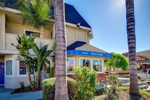 Un hotel con un cartel de 'Welcome', palmeras y un cielo azul despejado.