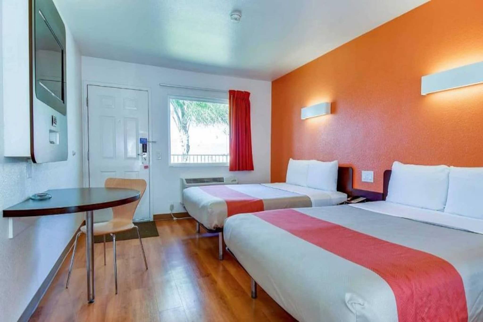 A hotel room with two beds, a desk, and a chair.