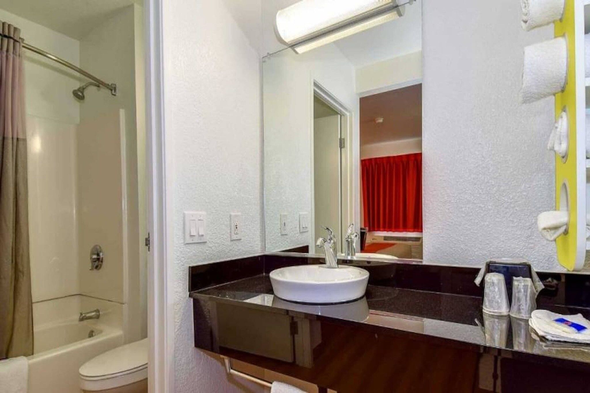 A bathroom with a bathtub, a sink, and a mirror.