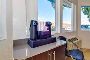 A room with a window, a coffee machine, and a chair.