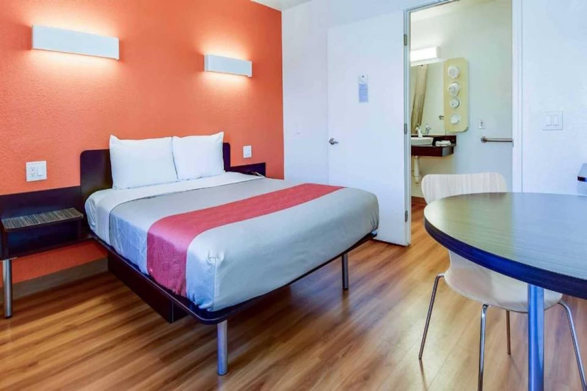 A hotel room with a bed, a desk, and a round table.