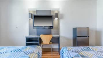 Habitación de hotel con dos camas, un escritorio, una silla, un televisor y un refrigerador.