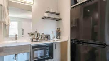 A modern kitchen with a stainless steel refrigerator, a built-in oven, and a microwave.