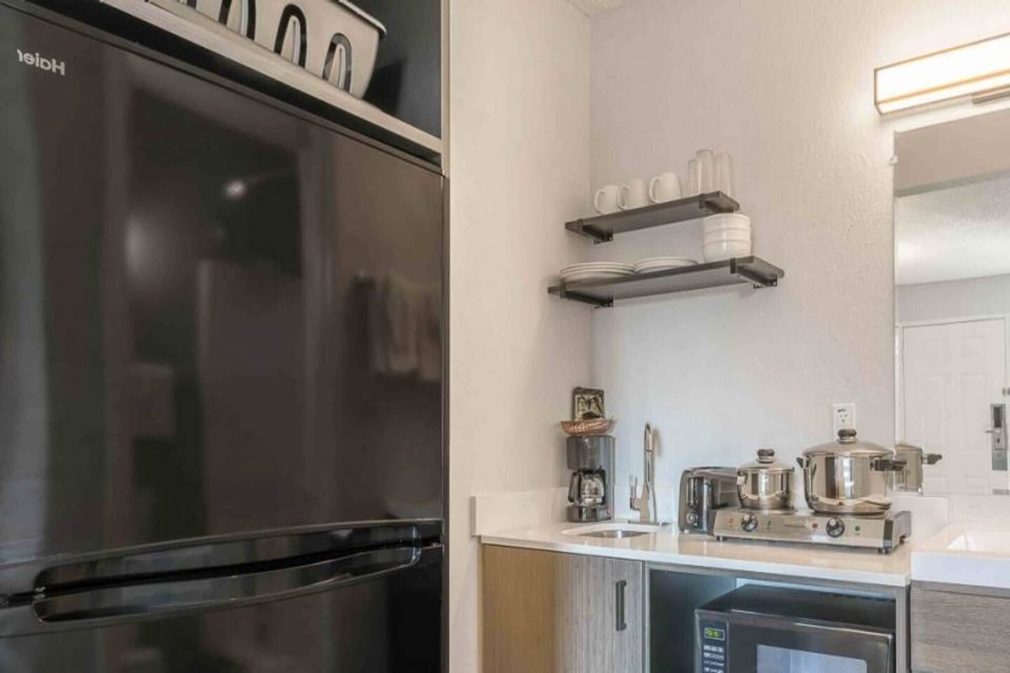 Une cuisine moderne équipée d’un réfrigérateur en acier inoxydable, d’une machine à café et d’un grille-pain posés sur le plan de travail.