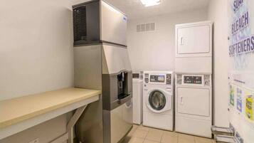 A compact laundry room with a stainless steel washer and dryer, a small sink, and a countertop.