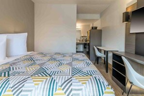 Habitació d'hotel amb un llit, escriptori i una cadira.