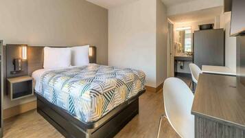 A modern hotel room with a bed, bedside tables, a desk, and a chair.