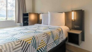 A hotel room with a bed, bedside tables, a wardrobe, and a window with curtains. - 1 Full Bed | Non-Smoking, Kitchen (Hayward)