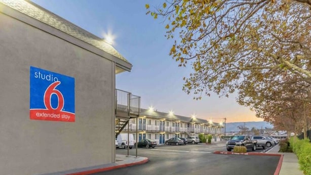 A hotel named Studio 6 with extended stay rooms, a parking area, and a view of the street. - 1 Full Bed | Non-Smoking, Kitchen (Hayward)