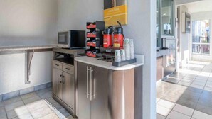 Una kitchenette con microondas, cafetera y saleros.