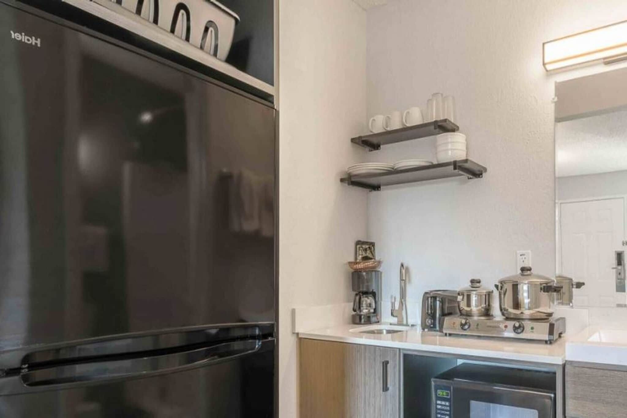 Une cuisine moderne équipée d’un réfrigérateur en acier inoxydable, d’une machine à café et d’un grille-pain posés sur le plan de travail.