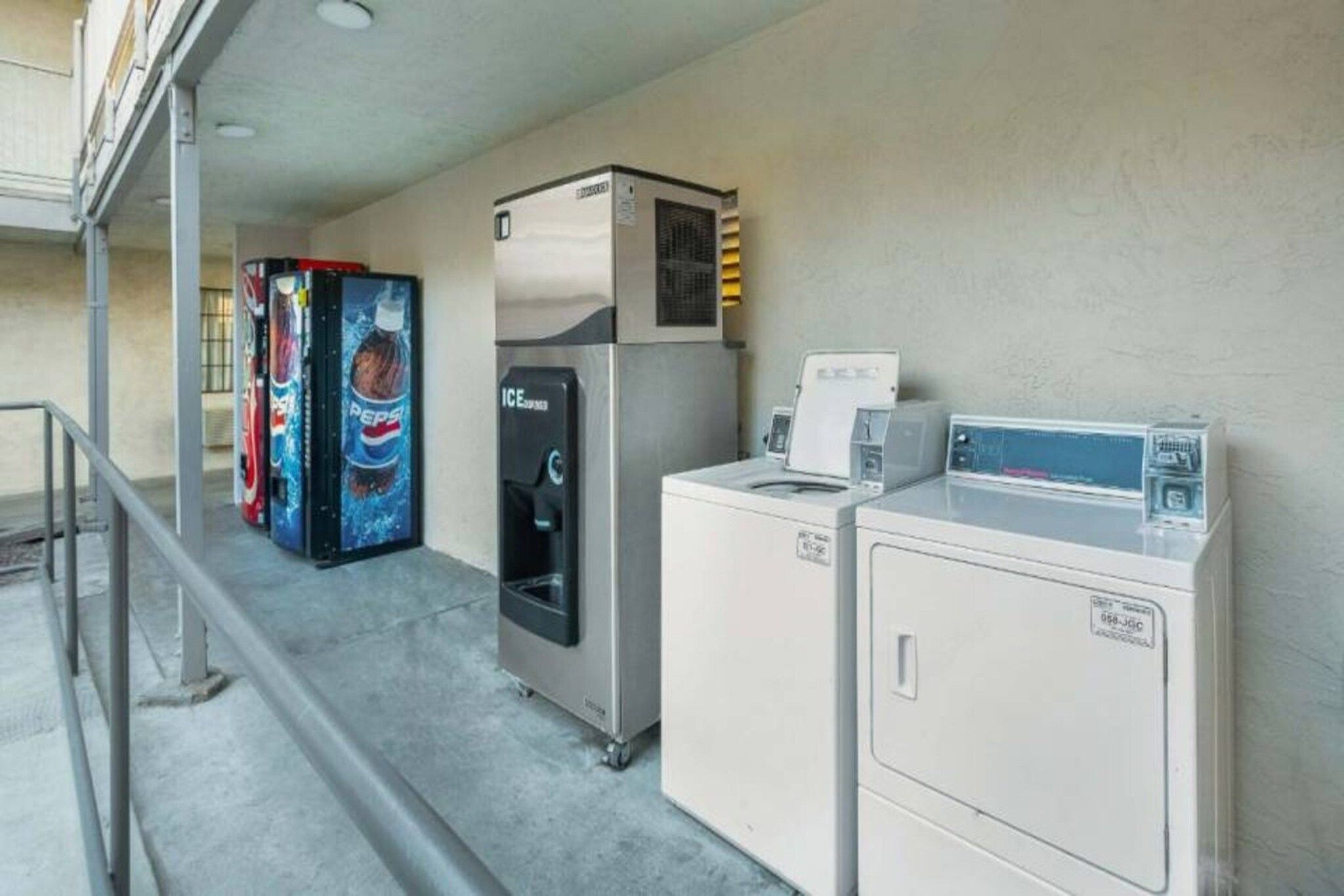 Ein Waschraum mit Kühlschrank, Getränkeautomaten und Waschmaschine.