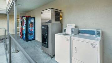 Ein Waschraum mit Kühlschrank, Getränkeautomaten und Waschmaschine.