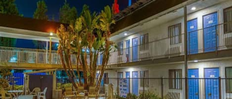 Un hôtel à plusieurs étages doté d’une piscine, d’un espace extérieur aménagé et d’une enseigne indiquant le numéro 6.